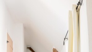 Ein Flur mit Steinwand, Holzbalken, Heizkörper und einer Tür.