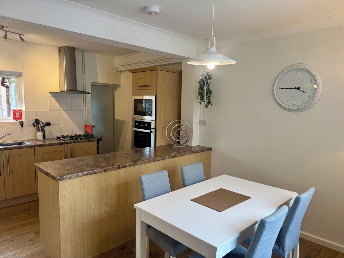 Una cocina moderna con una isla central, una mesa de comedor con sillas y un reloj de pared.