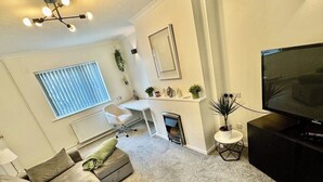 Una sala moderna con sofá, televisión, chimenea y comedor.