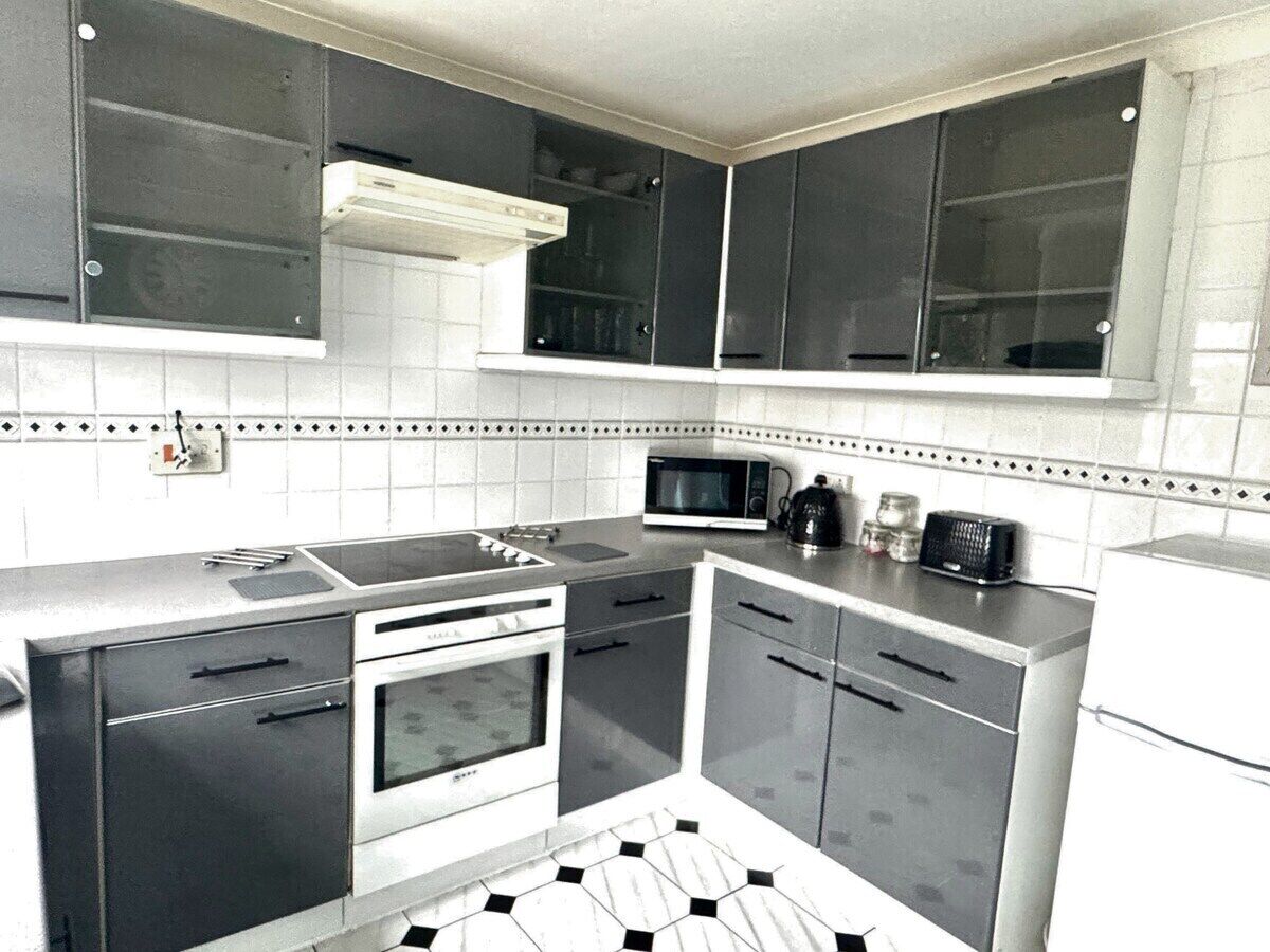 A compact kitchen with a microwave, stove, and cabinets.
