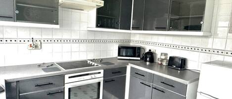 A compact kitchen with a microwave, stove, and cabinets.