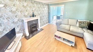 A living room with a fireplace, a sofa, a TV, and a bookshelf. - Homely 2 bedroom house, parking (Kidlington)