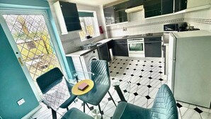 A compact kitchen with a dining area, a washing machine, and a window with a view. - Homely 2 bedroom house, parking (Kidlington)