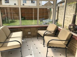 Une véranda donnant sur un jardin, avec deux canapés beige et une table.