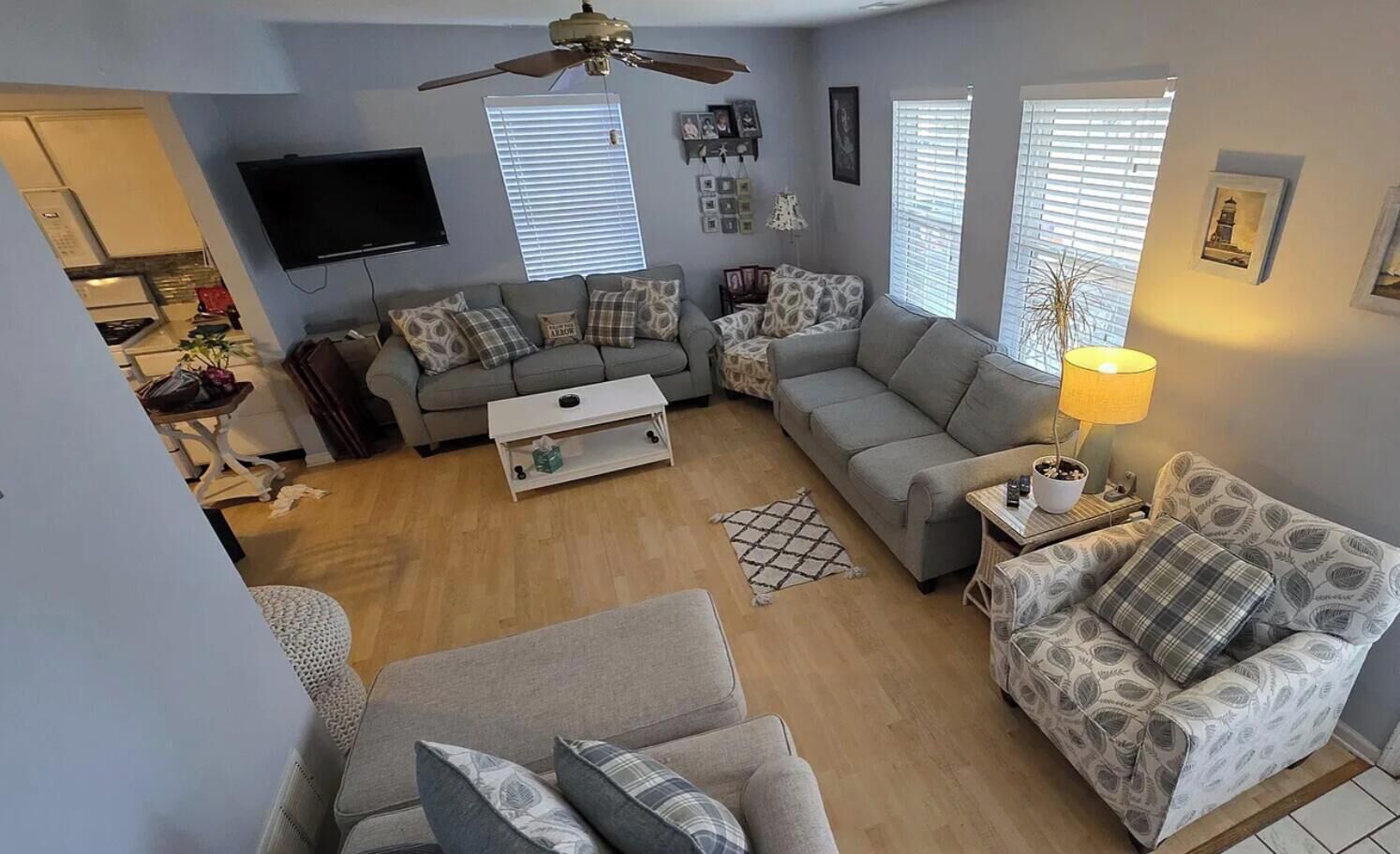 A living room with a sofa, a coffee table, a TV, and a ceiling fan.