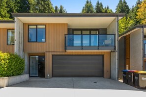 Ein modernes, zweistöckiges Haus mit Garage, großen Fenstern und einem Balkon.