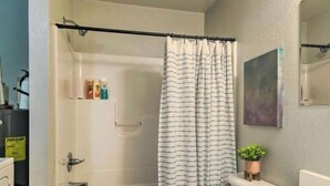 Een badkamer met bad, toilet en douchegordijn.
