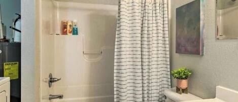 A bathroom with a bathtub, toilet, and shower curtain.