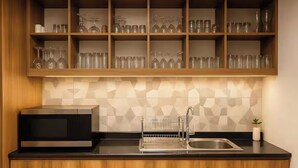 A kitchen with a microwave, sink, and wooden cabinets.
