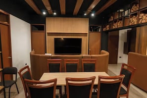 A modern living room with a TV, seating, and a dining area.