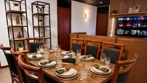 A dining area with a wooden table set for six, surrounded by wooden chairs.