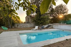 A rectangular swimming pool with two lounge chairs, a stone wall, and a tree in the background. - Ancien moulin rénové avec piscine privée (OLMETO)