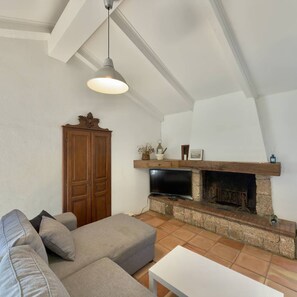 A living room with a sofa, a television, a fireplace, and a hanging light fixture. - Ancien moulin rénové avec piscine privée (OLMETO)