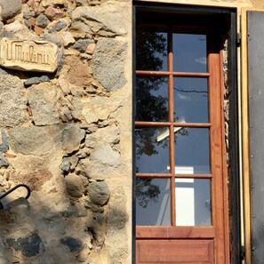 A stone wall with a wooden door and a window. - Ancien moulin rénové avec piscine privée (OLMETO)