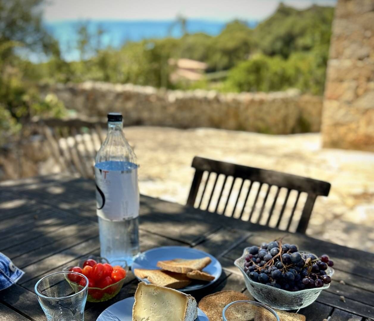 Et bord med en flaske, en skål med druer, et glas og tallerkener med mad.