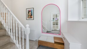 En trappa med vita spjälor, en inramad tavla på väggen och en spegel med en rosa ram.