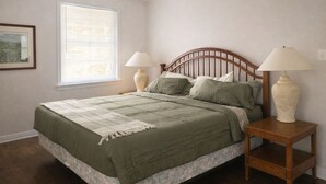 A bedroom with a bed, two bedside lamps, a window with blinds, and a framed picture on the wall. - Quintessential cottage walking distance to Oaklawn and minutes from downtown (Hot Springs)
