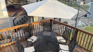 A deck with a table and chairs, an umbrella, and a railing. - Quintessential cottage walking distance to Oaklawn and minutes from downtown (Hot Springs)