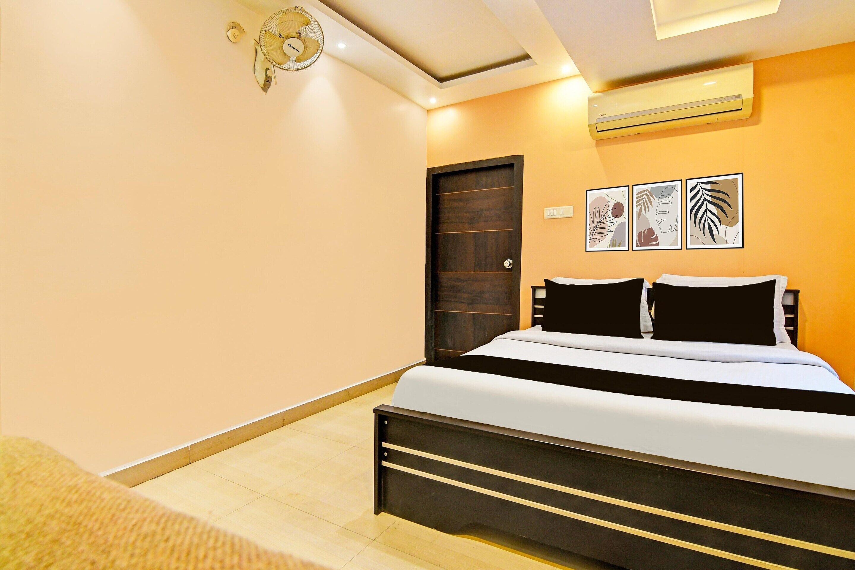 A bedroom with a bed, a door, an air conditioner, and wall art.