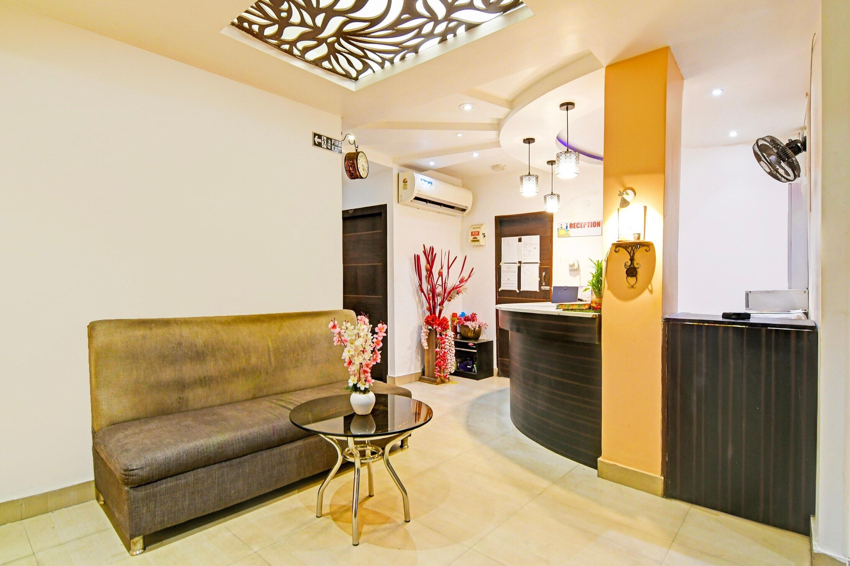 A reception area with a sofa, a round table with a vase, a reception desk, and a decorative ceiling feature.
