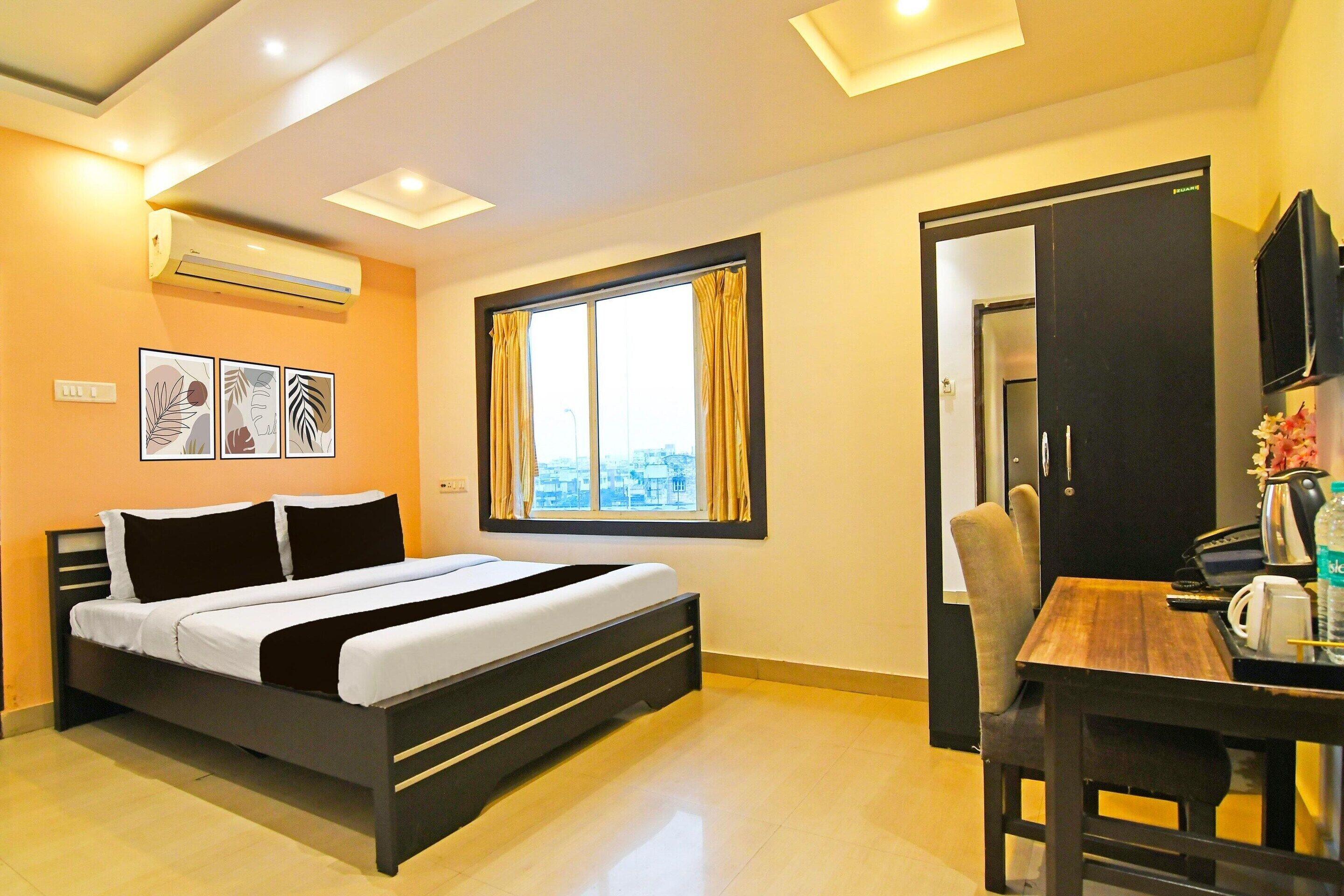 A hotel room with a bed, a window with curtains, a desk with a chair, and a television.