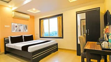 A hotel room with a bed, a window with curtains, a desk with a chair, and a television.