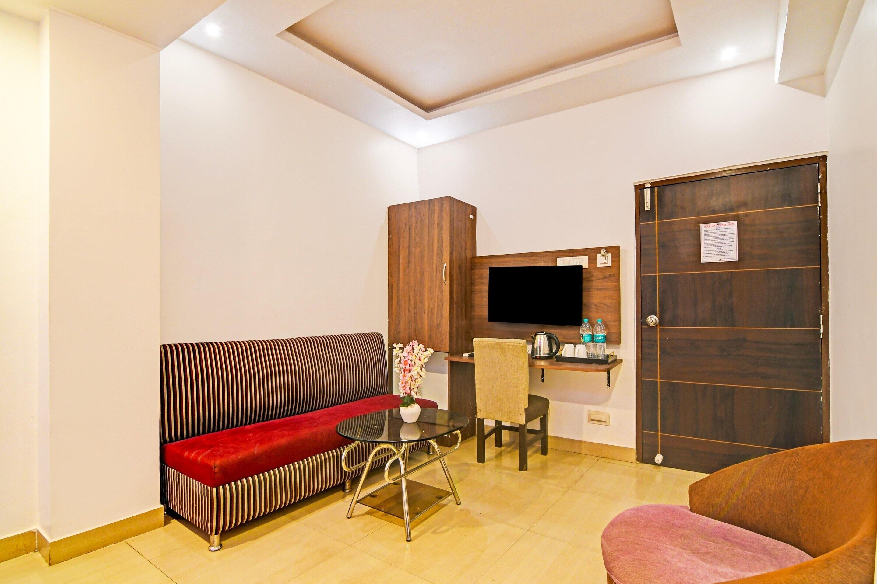 A living area with a sofa, a chair, a table, a TV, and a wooden door.