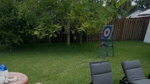 Un giardino sul retro con un tavolo da picnic, sedie relax e una tartaruga sull'erba.