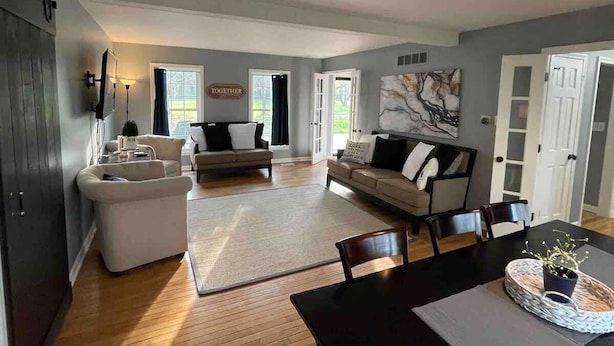 A spacious living area with a sofa set, a dining table, and a kitchen area with a refrigerator.
