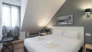 Ein Schlafzimmer mit einem Bett, einem Nachttisch, einer Lampe, einem Heizkörper und einem Fenster mit Vorhängen.