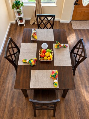 A dining table with four chairs, a fruit basket, and colorful napkins. - Ma G’s Downtown Soufrière Townhouse (Soufriere)