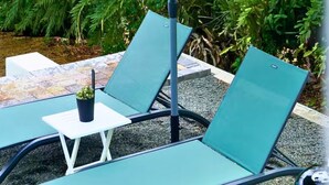 A patio with two green lounge chairs and a small table, surrounded by greenery. - Westpunt Villa  l 2BR Near Turtle Beach (Westpunt)