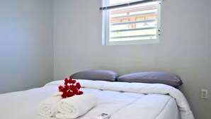 A bedroom with a bed, pillows, a window, and a red flower arrangement. - Westpunt Villa  l 2BR Near Turtle Beach (Westpunt)