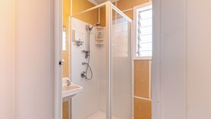 A glass-enclosed shower area with a white sink and storage shelves. - Classic 3 Bedroom Holiday Home (Twizel)