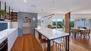 Una cocina moderna con una isla central, suelo de madera y una zona de comedor con mesa y sillas.