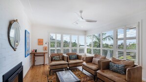 Una sala de estar con sofás de cuero, chimenea y ventanas grandes con contraventanas.