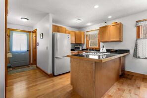 Eine moderne Küche mit Holzausbau, einer Kochinsel und einem Kühlschrank.
