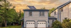 Ein zweistöckiges Haus mit Garage, Solaranlage und überdachter Veranda.