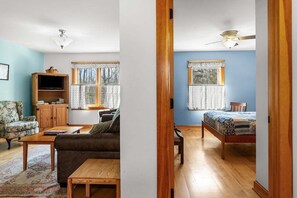 Ein Zimmer mit einer Couch, einem Holztisch, einem Fernsehschrank und einem Bett.