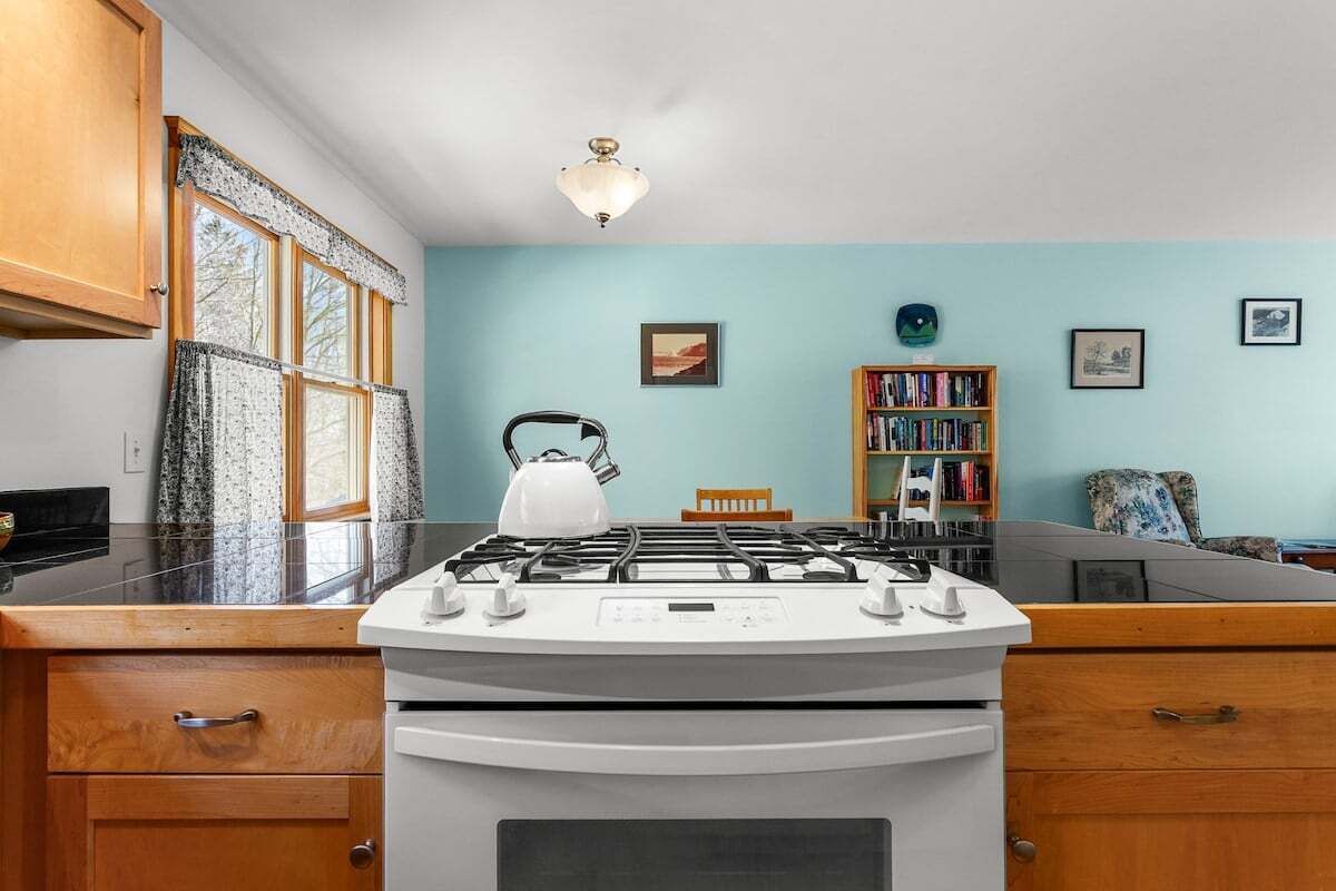 Une cuisine équipée d’une cuisinière, d’une bouilloire, d’une bibliothèque et d’une chaise.