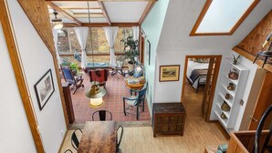 Una habitación con techo de madera, comedor con mesa y sillas, pequeña cocina y vista por una ventana.