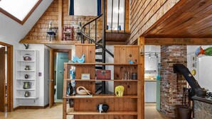 Una habitación estilo loft con una escalera de madera, una pared de ladrillo y un estante con varios objetos decorativos.