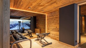 Ein modernes Fitnessstudio mit Holzwänden, einem großen Spiegel und verschiedenen Trainingsgeräten.