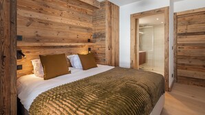 Ein Schlafzimmer mit einem Holz-Kopfteil, einem Bett mit einer strukturierten Decke, einem Nachttisch und einer Tür zu einem Badezimmer.