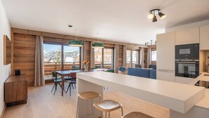 Eine moderne Küche mit Kochinsel, Barhocker und Essbereich mit Blick.