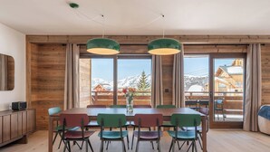 Ein Essbereich mit Holztisch, Stühlen und Blick auf schneebedeckte Berge.