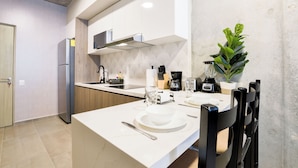 Una cocina moderna con armarios blancos, microondas integrado y cafetera.