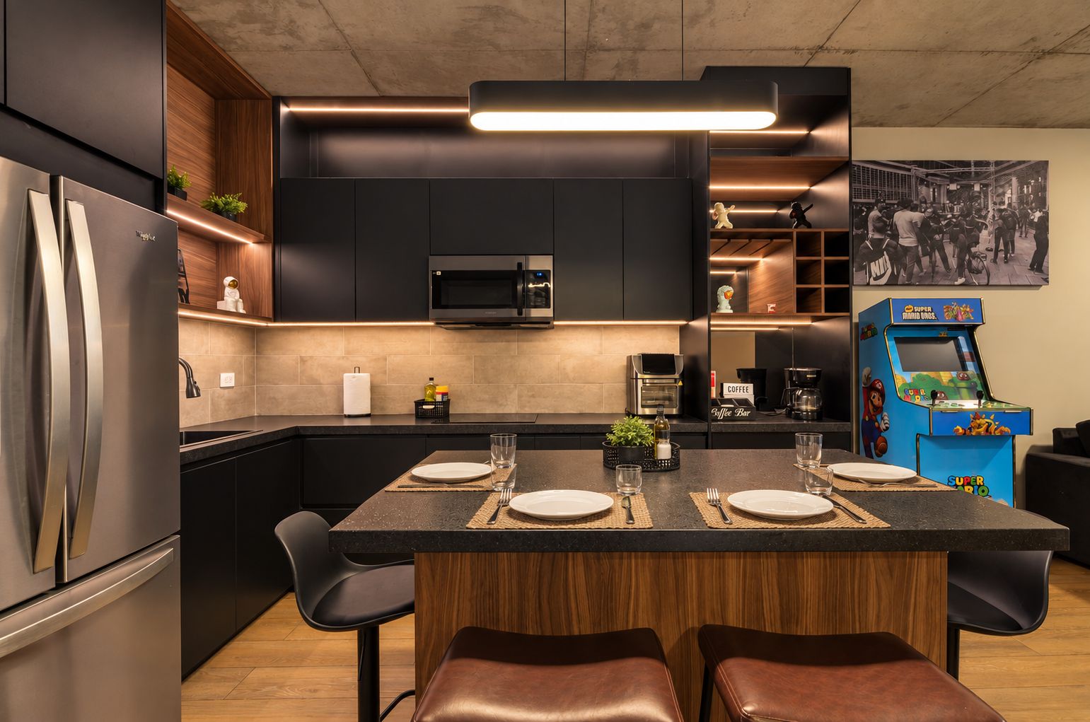 Una cocina moderna con una isla central, electrodomésticos integrados y una máquina recreativa retro.
