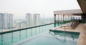 A rooftop infinity pool with a city view, lounge chairs, and a modern architectural design. - UNA Torre (Monterrey)