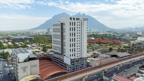 A high-rise building with multiple floors, a stadium, and a highway with vehicles. - UNA Torre (Monterrey)